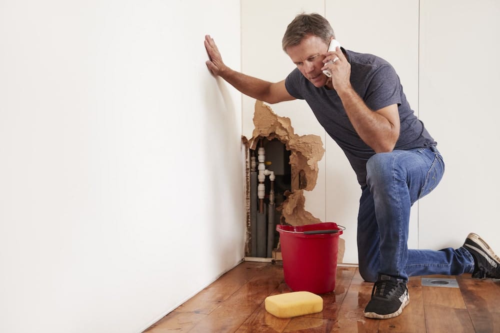 middle-aged-man-with-a-burst-water-pipe-phoning-for Boise Water Damage Restoration Help