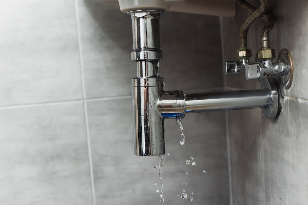 Damaged steel pipe in bathroom on grey background